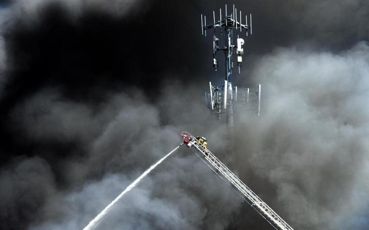 
Central Pierce fireman is framed by a cloud of smoke as he climbs to the top of the ladder to fight a fire at the Public Storage units in Puyallup. 
