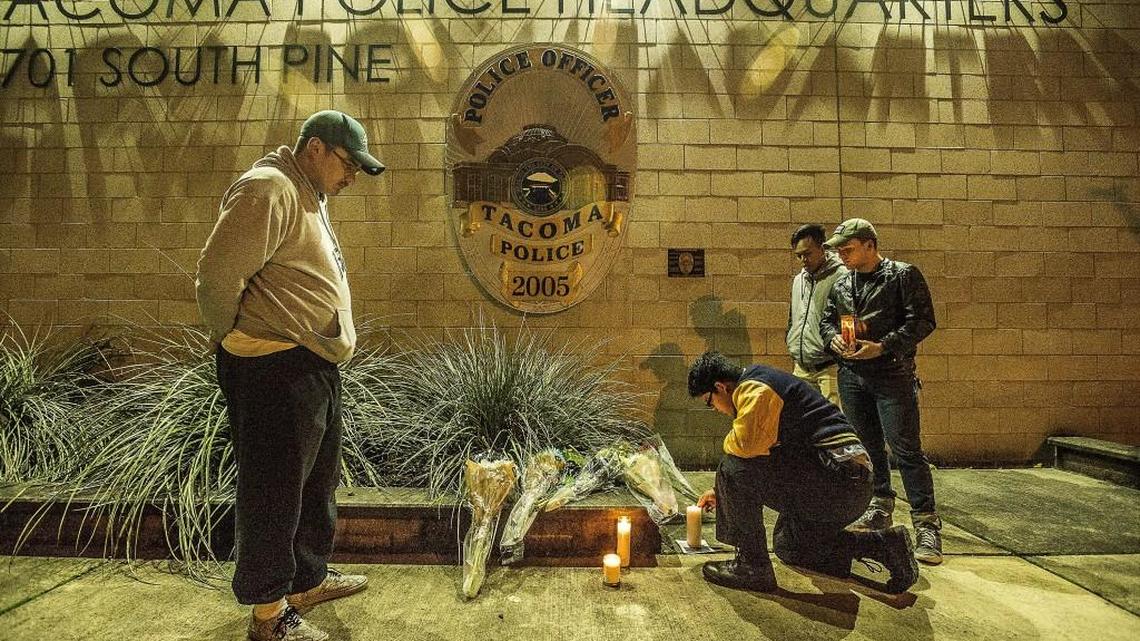 Eli Gonzalez lights a candle at Tacoma Police headquarters in honor of slain officer Reginald “Jake” Gutierrez with Sam Bissen, left, in front of Tacoma Police headquarters on South Pine Street late Wednesday night.