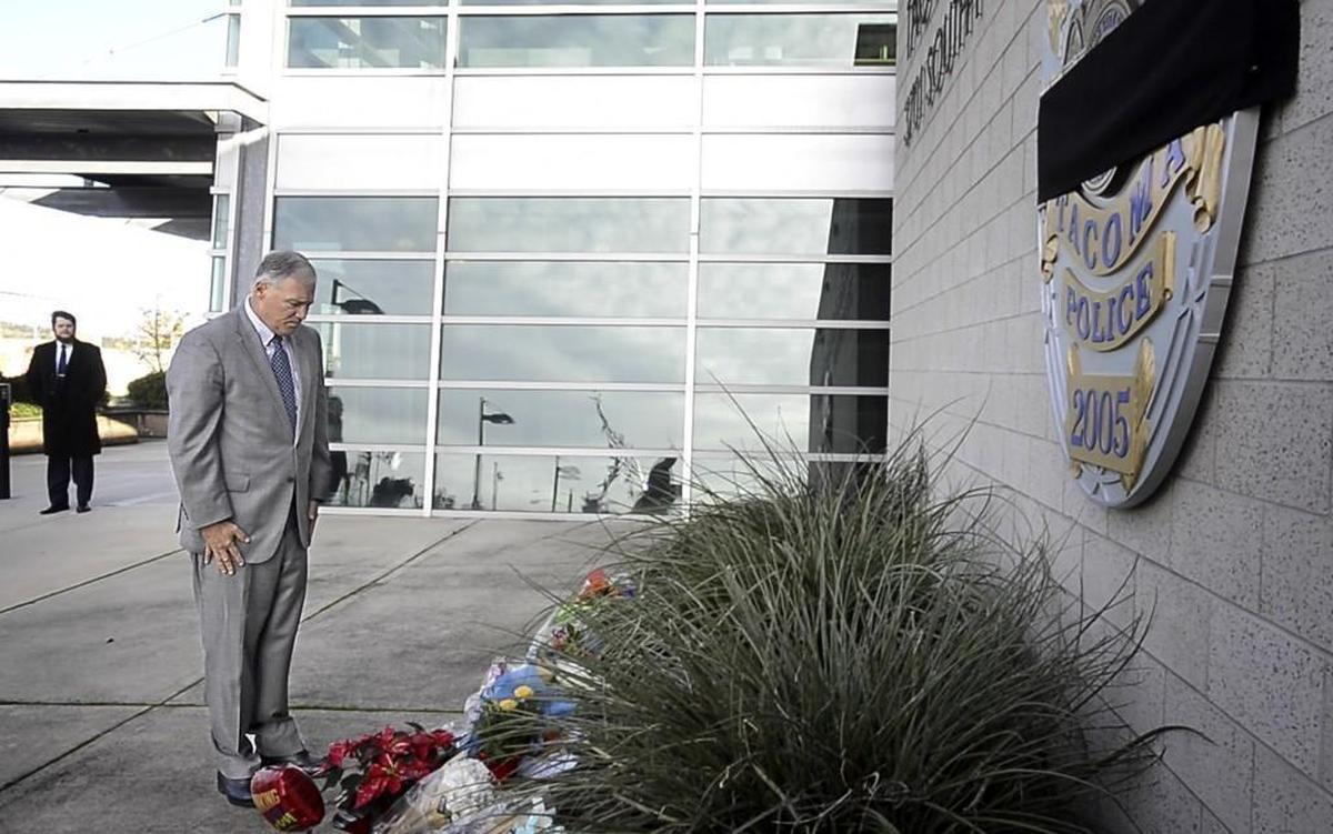 Washington Gov. Jay Inslee pays respects after placing flowers at a memorial in front of Tacoma Police headquarters to slain Tacoma police Officer Jake Gutierrez in Tacoma on Dec. 1.