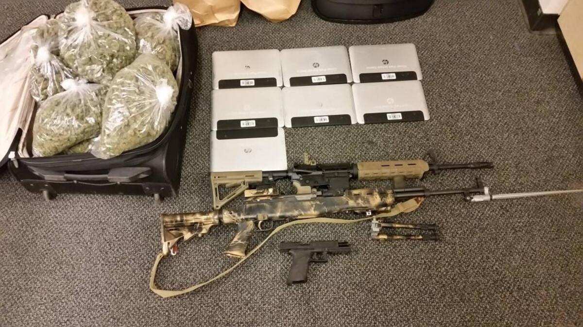 Lakewood police seized a suitcase with 10 pounds of marijuana, seven stolen tablet computers and three guns from a home near Clover Park High School after serving a search warrant Wednesday. Two men were arrested in connection with the case.