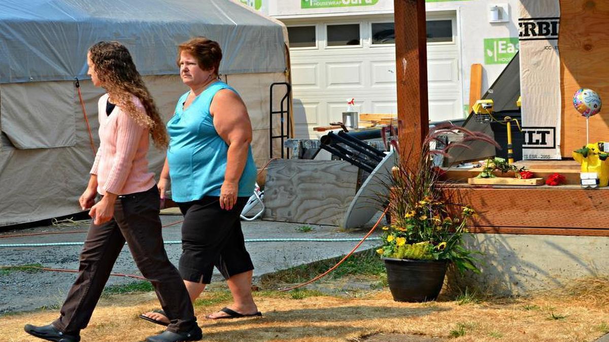 
Dale Andersen, right, and her daughter, Megan Andersen, walk away after leaving a clutch of roses at the place where their neighbor, Richard Johnson, was shot to death in Puyallup on Tuesday. “He was a friend to everyone,” Dale Andersen said of Johnson.
