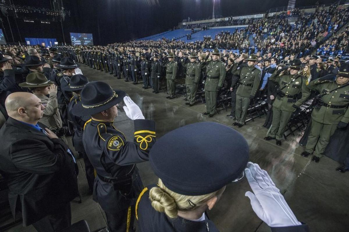 Law enforcement officers in dress uniforms salute during a Dec. 9 memorial service at the Tacoma Dome for slain Tacoma police Officer Reginald “Jake” Gutierrez.