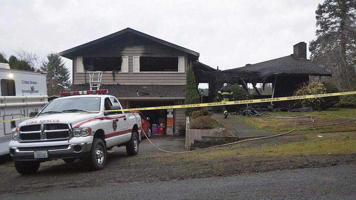 A firefighter walks to the scene of a house fire where three children perished Friday in Centralia. Police say the fire woke the woman sleeping downstairs and she couldn't get to her children.
