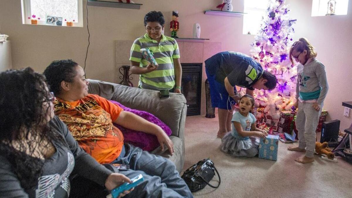 The kids try to figure out what's inside their wrapped Christmas presents as parents Daisy Rivera (left) and Mahogany Corioso keep the secrets, December 20. The children are (clockwise from right) Gisselle Guzman-Rodriguez, Annaleigh Guzman-Rodriguez, Gabriel Guzman-Rodriguez, and Adrian Rodriguez (bending over). Corioso and Rivera were engaged to be married, the kids were adopted, and the family found a new home, all in 2015. And the tree is decorated in their planned wedding colors.