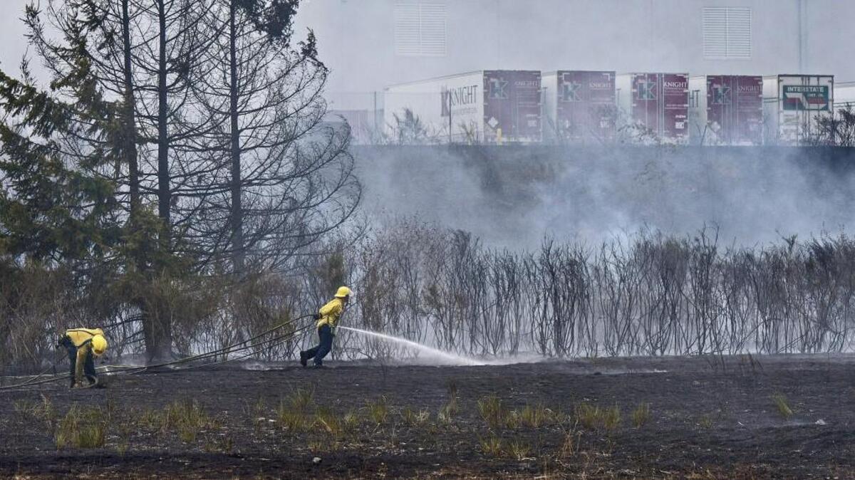 
Firefighers mop up a brush fire near the Ikea distribution center in Frederickson, August 28, 2015.
