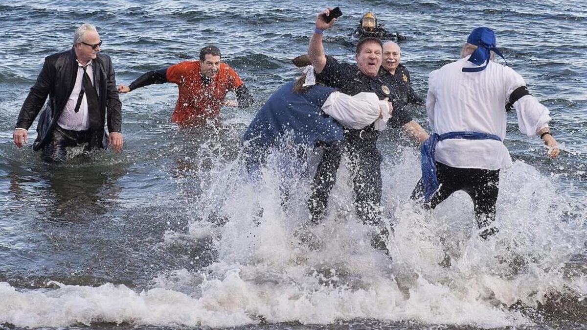Fircrest Police Chief John Cheesman pretends to save a smartphone while being dragged off of Owen Beach in Tacoma at the 2015 Polar Plunge to support Special Olympics Washington.