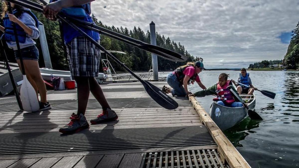 Camp counselor Katy Nardi grabs the canoe Daejonna Artis, 10, is riding at Camp Seymour on the Key Peninsula in August 2016.