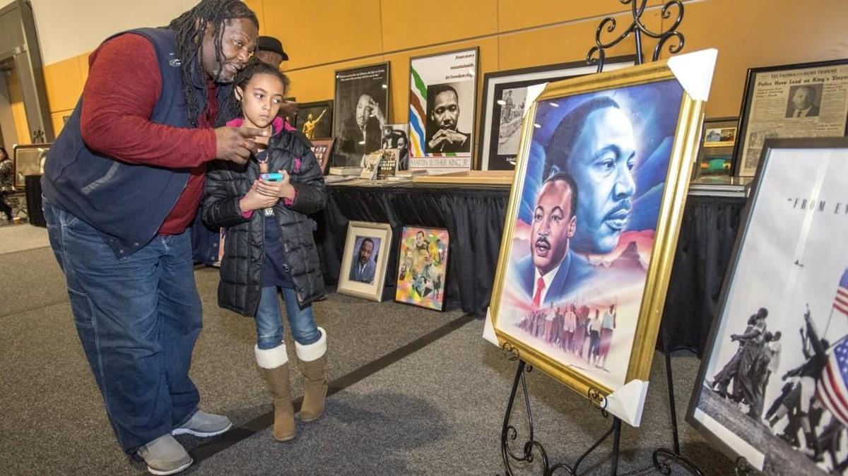 Nate Wise of Graham discusses the historical importance of Dr. Martin Luther King Jr. with his granddaughter Lillian Koch, 9, of Puyallup at the celebration of his birthday at the Tacoma Convention & Trade Center on Monday. Koch said she had been studying Dr. King’s famous “I Have a Dream” speech in school. “We learned that he was trying to get black and white people to live together in unity,” she said. The personal collection of King memorabilia was brought to the event by Terri and James Broggin of Tacoma.