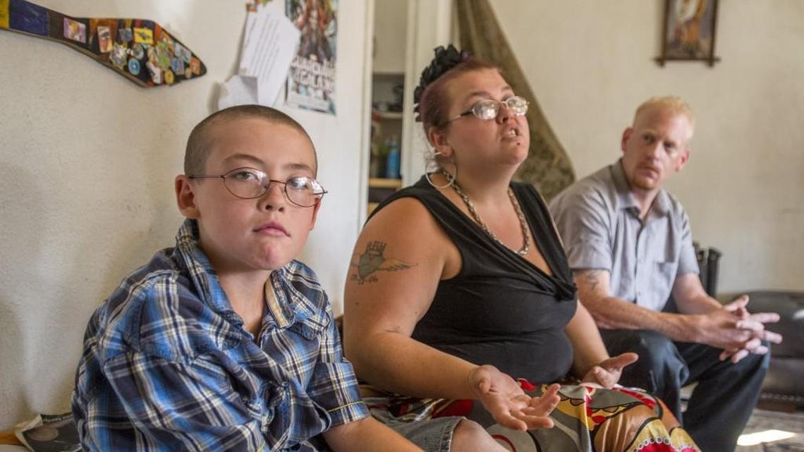 Roland Ware, who has attended Chief Leschi Schools since kindergarten, just found out that he can’t attend this year, because he’s not enrolled in a recognized tribe. Next to him in the living room of the family home in Tacoma are his mom, Breanna McNeece, who is of Cherokee heritage, and her boyfriend, Jeff Etue.