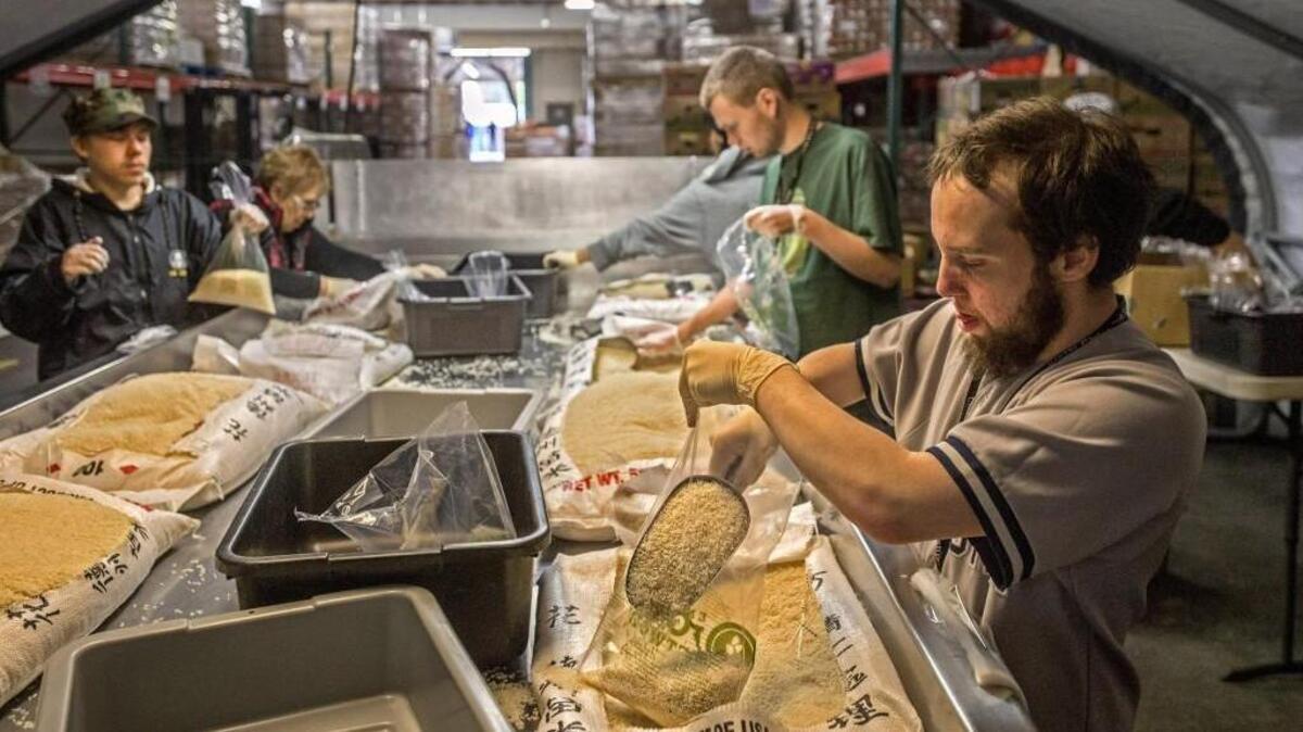 Bobby Costello, right, and others from Clover Park School District’s Alfaretta Transition Program rebag rice at Emergency Food Network.