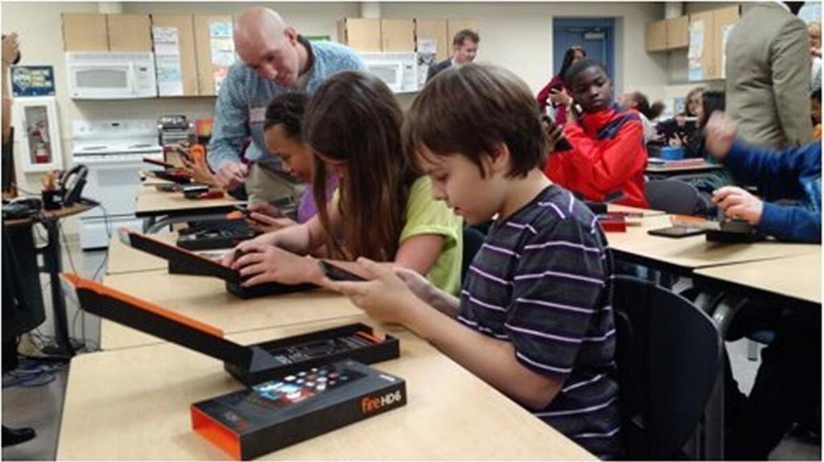 
Students at Pioneer Middle School show off their new Kindle devices Monday to Greg Zielinski of Amazon’s DuPont fulfillment center. 
