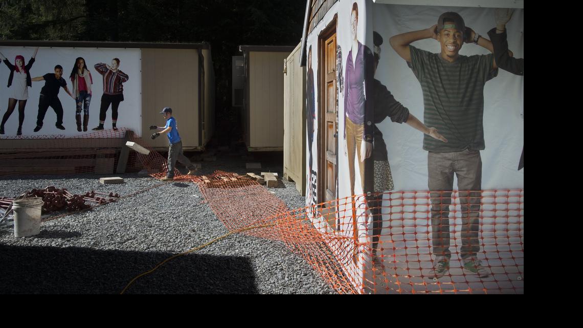 
Josh Turner with Robbins and Co. tosses a foundation block Tuesday for one of 15 portable SAMI classrooms that were moved to the old logging camp at Point Defiance Park.
