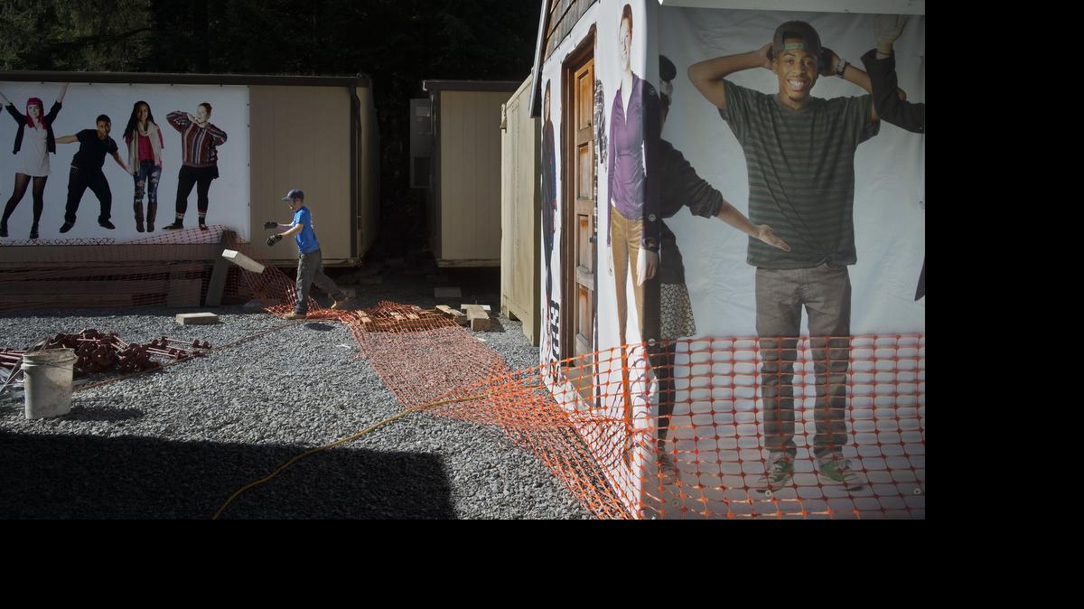 
Josh Turner with Robbins and Co. tosses a foundation block Tuesday for one of 15 portable SAMI classrooms that were moved to the old logging camp at Point Defiance Park.
