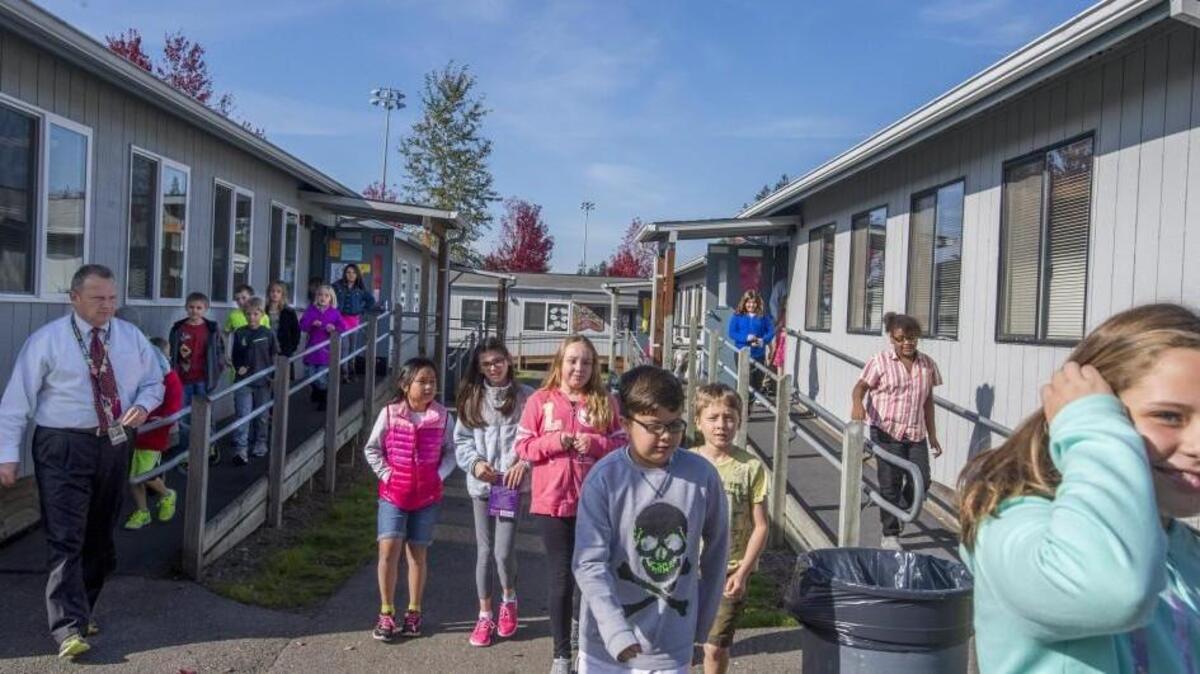 
Fourth-graders stream out of portable classrooms at Zeiger Elementary in South Hill. The school holds classes and programs in 11 portable classrooms. If a proposed bond measure passes, Puyallup school officials estimate, the need for 100 of the district’s 122 portable elementary classrooms will be eliminated.
