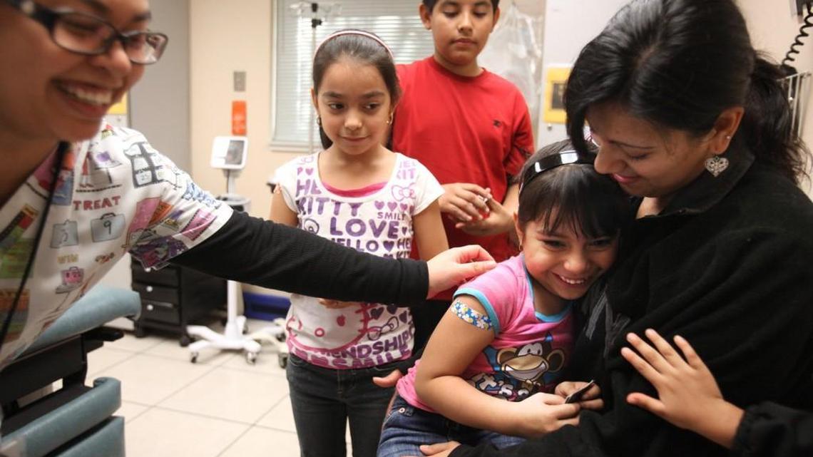 Gessel Cisneros, 5, is comforted by family after receiving a flu vaccination shot from medical assistant Jameela Yousos, left, at the Sea Mar Clinic in west Olympia in January 2013.