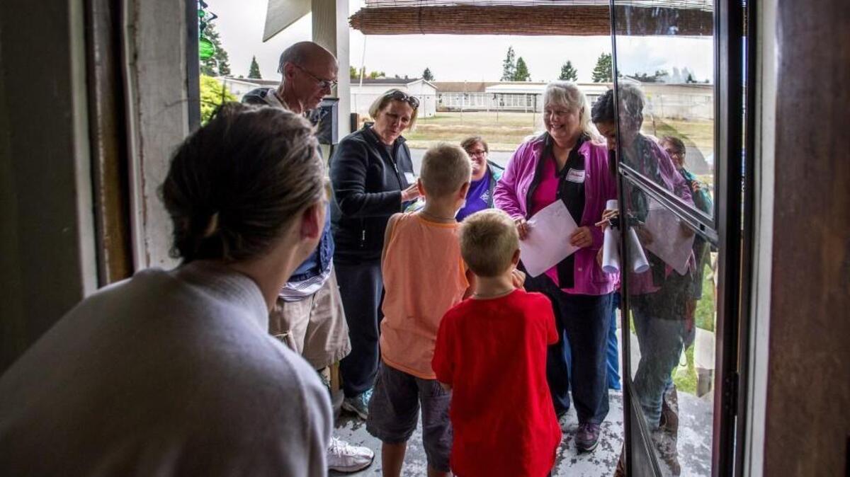 
A group of teachers from Lyon Elementary School on Tacoma’s East Side meet third-grader Gabe Nowak and first-grader Logan Nowak in their home behind the school on Tuesday. The teachers were walking around the school’s neighborhood to meet people and familiarize themselves with the community.
