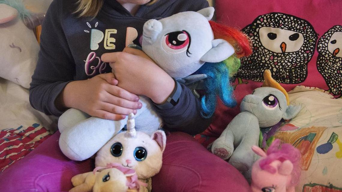 Stella Keating, 11, snuggles her beloved collection of stuffed animals in her bedroom. Keating, a transgender girl, feels a particular kinship with the unicorns. “They’re picky. Once they choose something, there’s no going back, which is what I do a lot. They’re completely unique.”