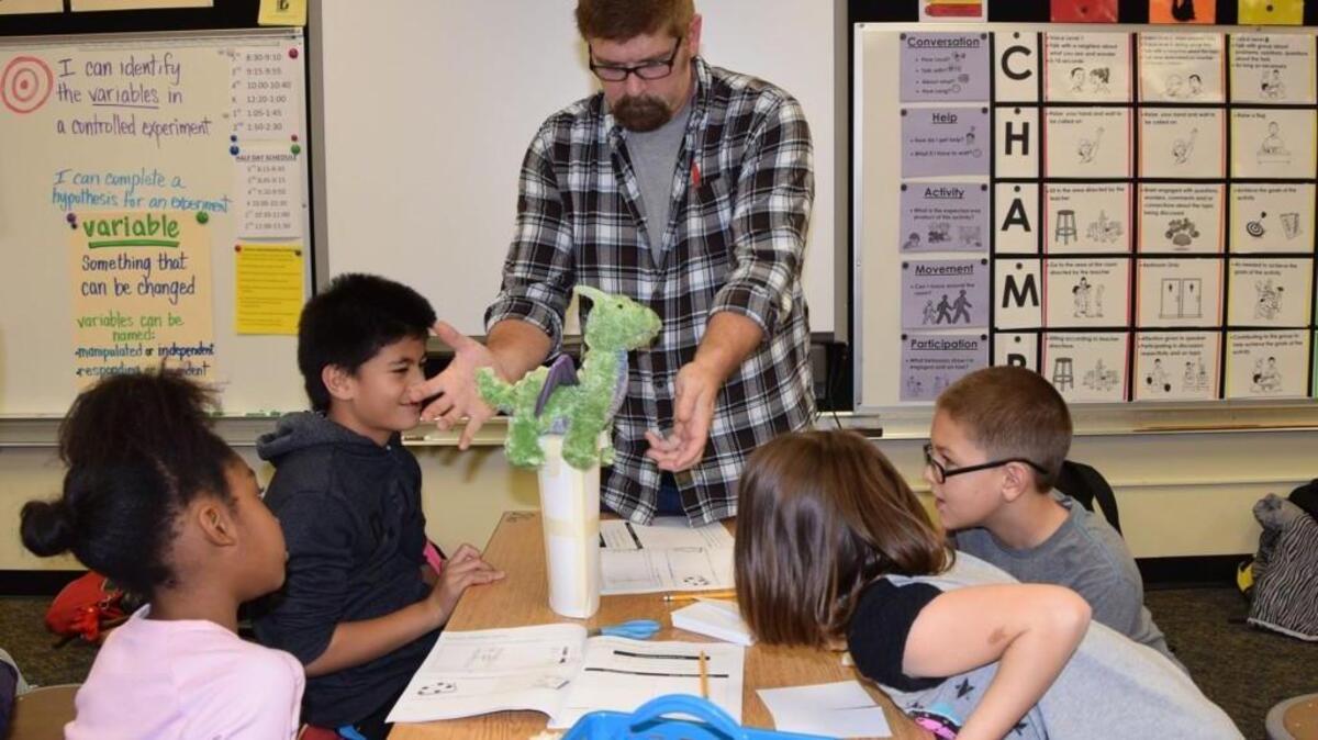 Teacher Jeff Wilson checks to see if a platform designed and built by Dower Elementary students will hold the Dower dragon mascot. The students created the platform as part of an after- school science program.