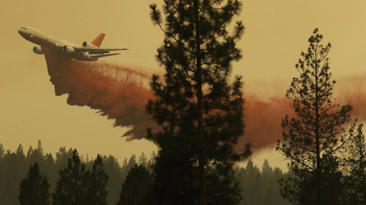 An airplane tanker flies through smoky air as it drops fire retardant on a wildfire that flared up in the late afternoon near Omak, Washington in August 2015. State officials recently released a 20-year plan they hope will reduce wildfire risk and improve the health of forests in Eastern Washington.