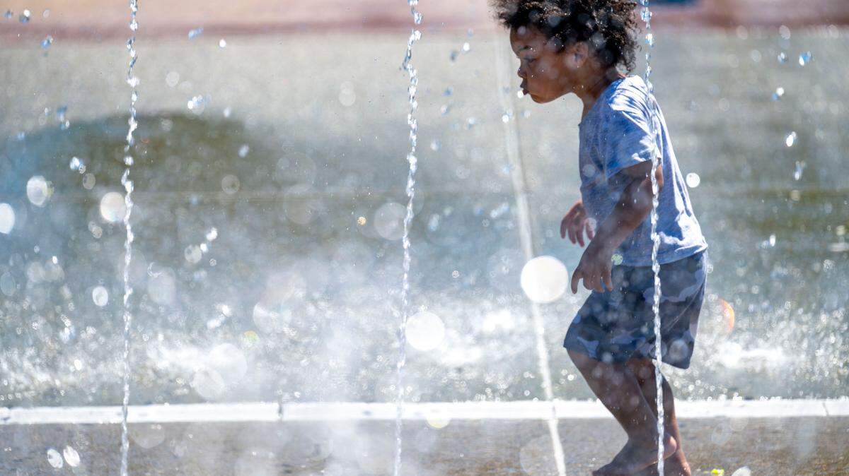 Khy’Shon Lopes, 2, of Tacoma, walks through an archway of water at the splash pad at Verlo Park in Tacoma, Wash. on Tuesday, July 19, 2022.