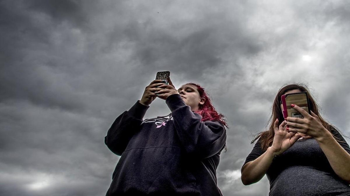 Angela Helgesson, 19, left, and her friend Mariah Pope, 27, follow clues on their phones walking on the damp, fresh-cut grass of Thea's Park in search of Pokemon to catch.
