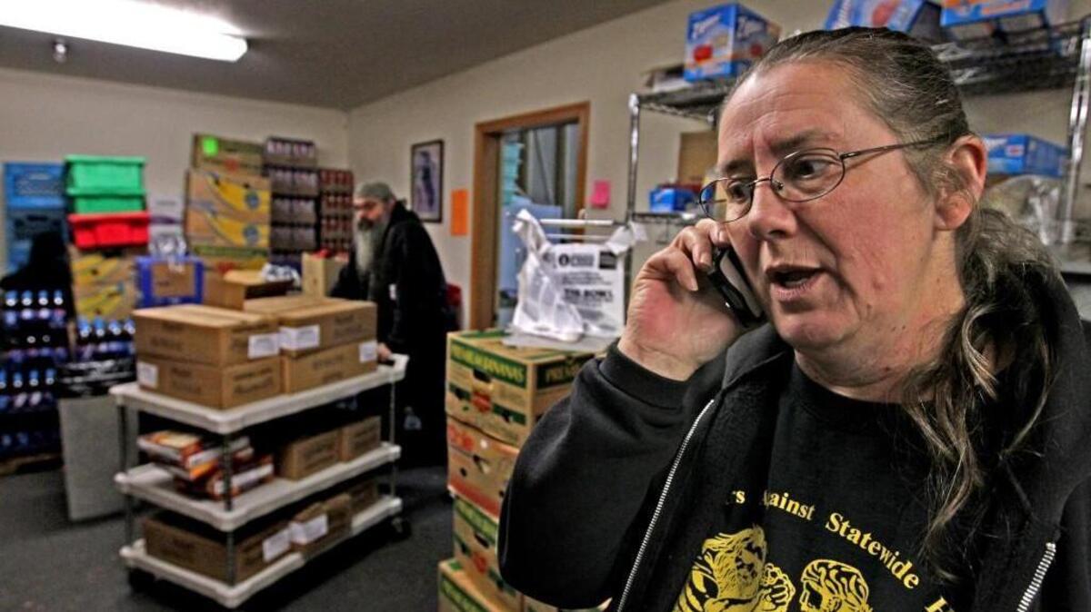 Vickie Houk, manager of Bikers Against Statewide Hunger (BASH) works the phones while her husband, Bob, wheels a cart full of pies into the BASH food bank in Tacoma during the annual turkey giveaway Friday Nov. 16, 2012. The biker non-profit brother and sisterhood provided 287 Thanksgiving boxes with all the fixings.
