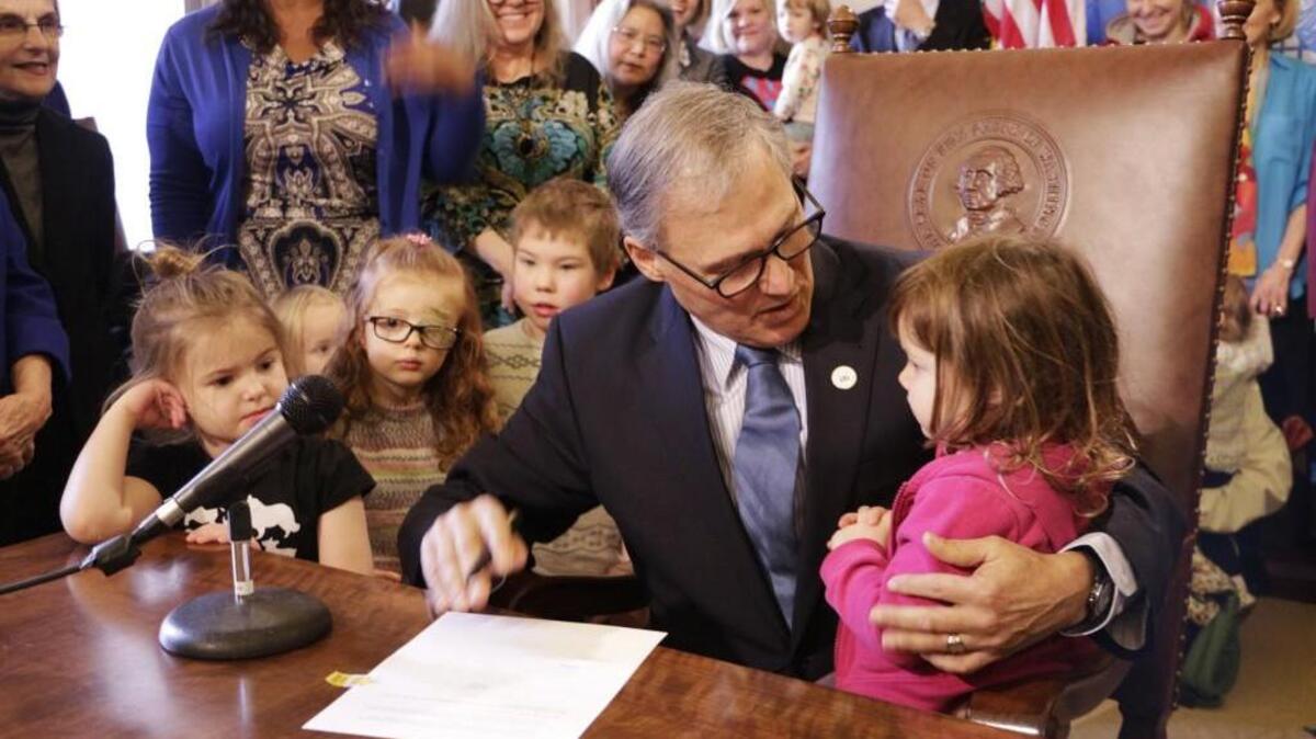 Surrounded by children, Gov. Jay Inslee gets ready to sign an executive order creating a commission that will present recommendations about a proposed new state agency to deliver services to vulnerable children and families, Thursday, Feb. 18, 2016, in Olympia.