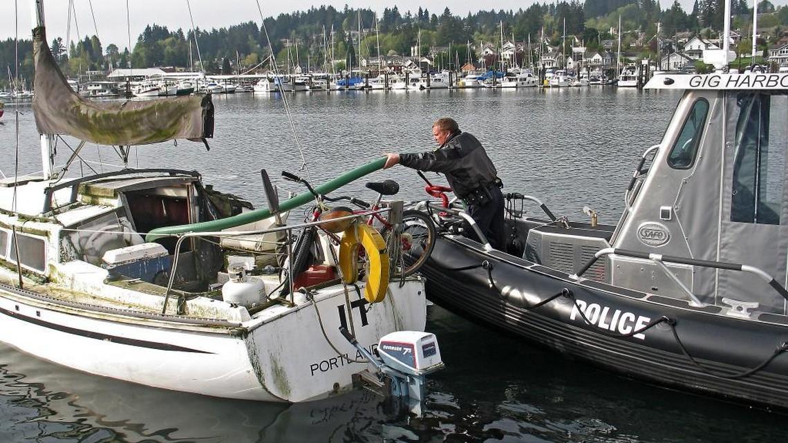 Gig Harbor police Chief Kelly Busey drains an abandoned boat of hazardous materials in 2009 in Gig Harbor. After police pumped the boat out several times, the owner eventually removed it from the harbor, Busey said.