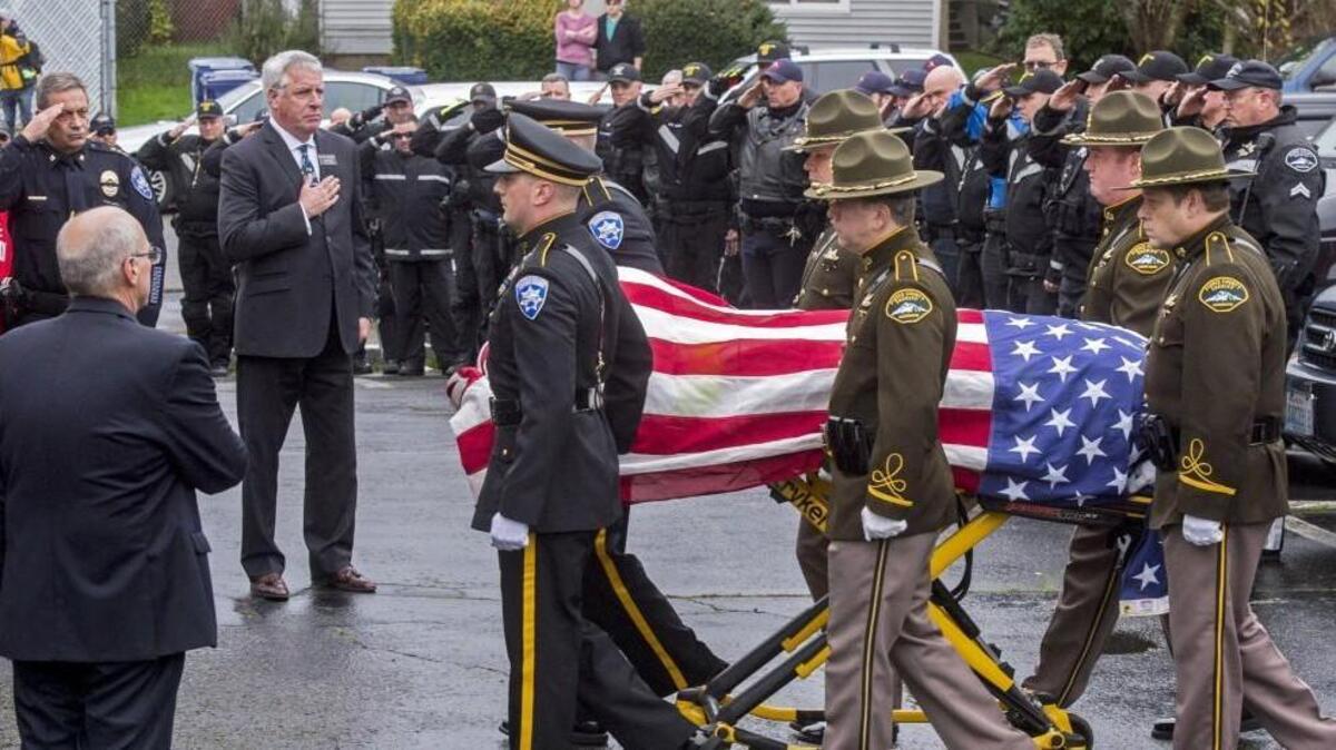 An honor guard of Tacoma police officers and Pierce County sheriff’s deputies rolls a casket carrying the body of slain Tacoma Officer Reginald “Jake” Gutierrez into Tuell-McKee Funeral Home on Friday. A public memorial for Gutierrez will be held Friday at the Tacoma Dome, and it will be open to the public.