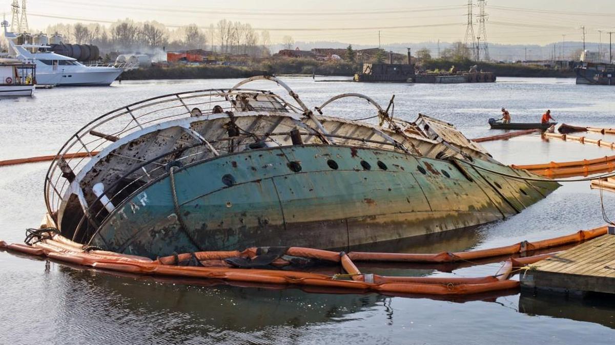 Workers from Ballard Diving move containment booms that surround the partially submerged MV Helena Star in Tacoma’s Hylebos Waterway in November 2013. The United States recently sued the ship’s six owners for the cost of environmental cleanup required after it sank in the Hylebos in 2013.