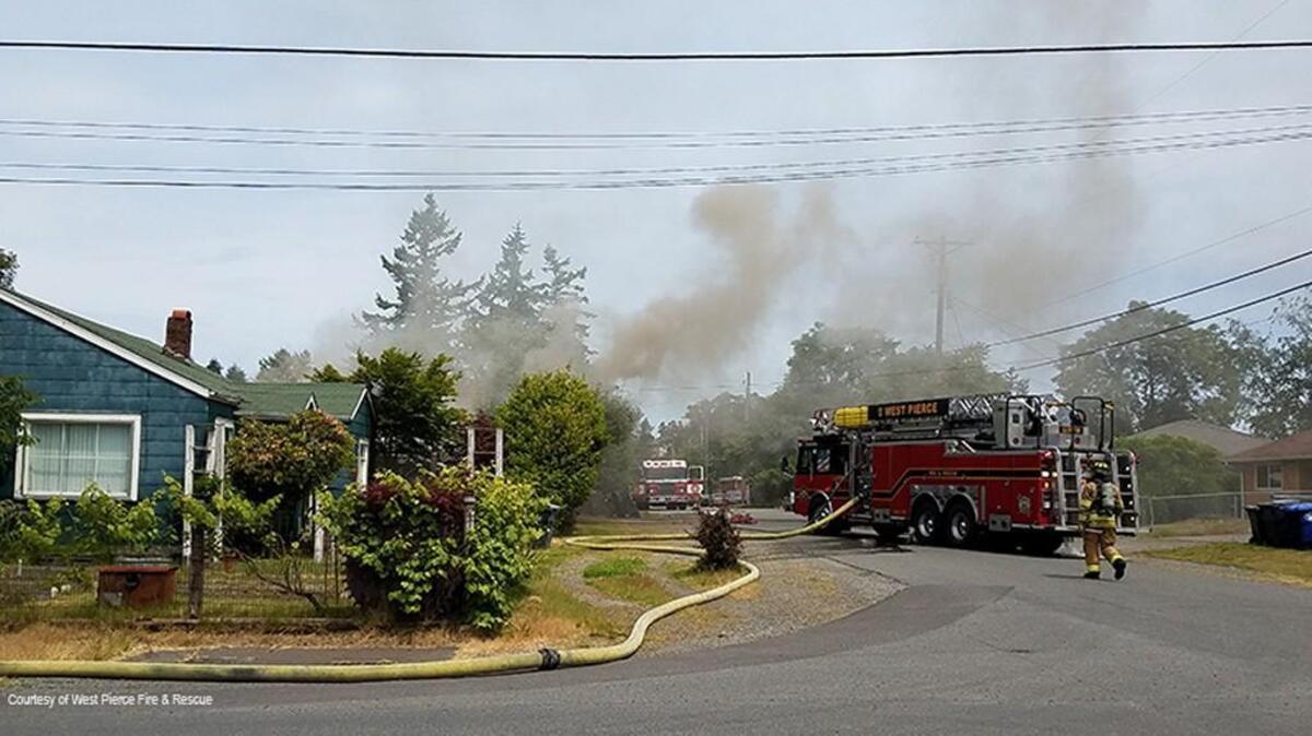 Orange-tinted smoke emanates Wednesday afternoon from a house fire in unincorporated Pierce County.