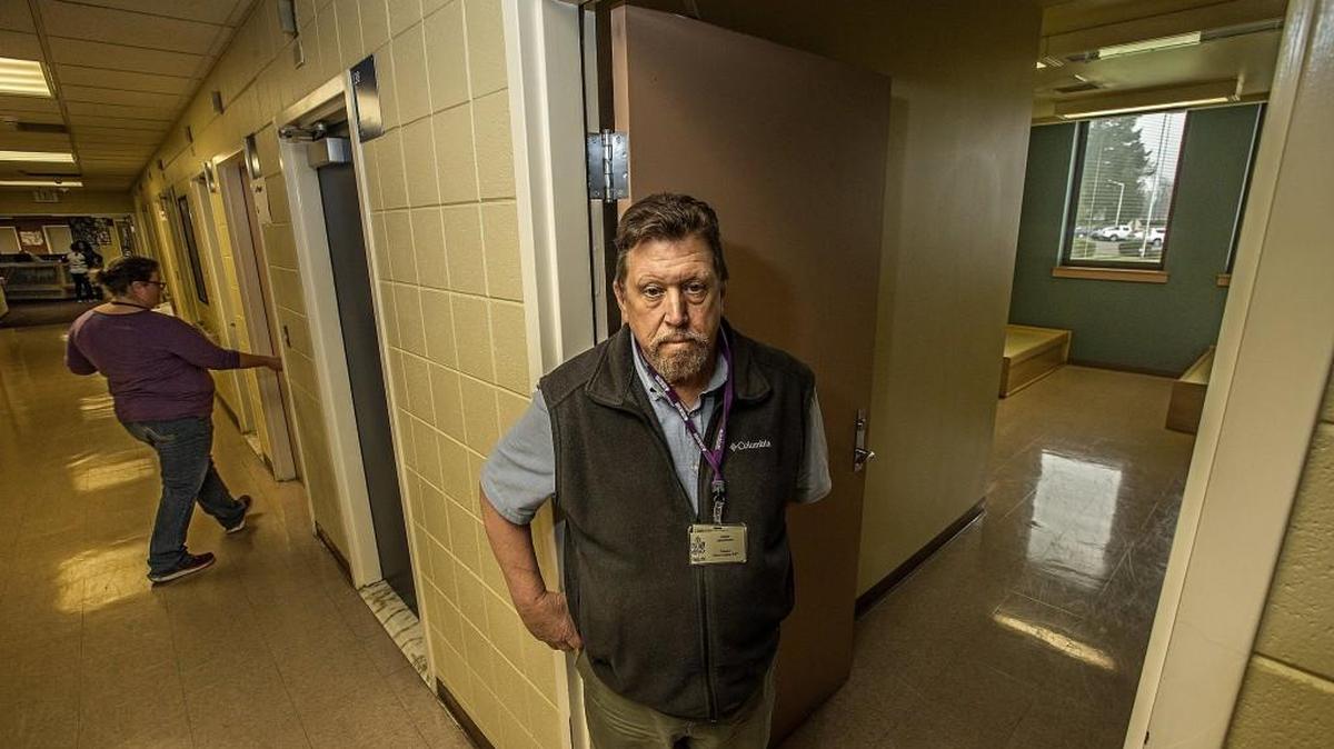 Jim Presson, administrator of the Telecare Recovery Partnership, stands in the doorway of an unoccupied room while a staff member checks rooms with patients.