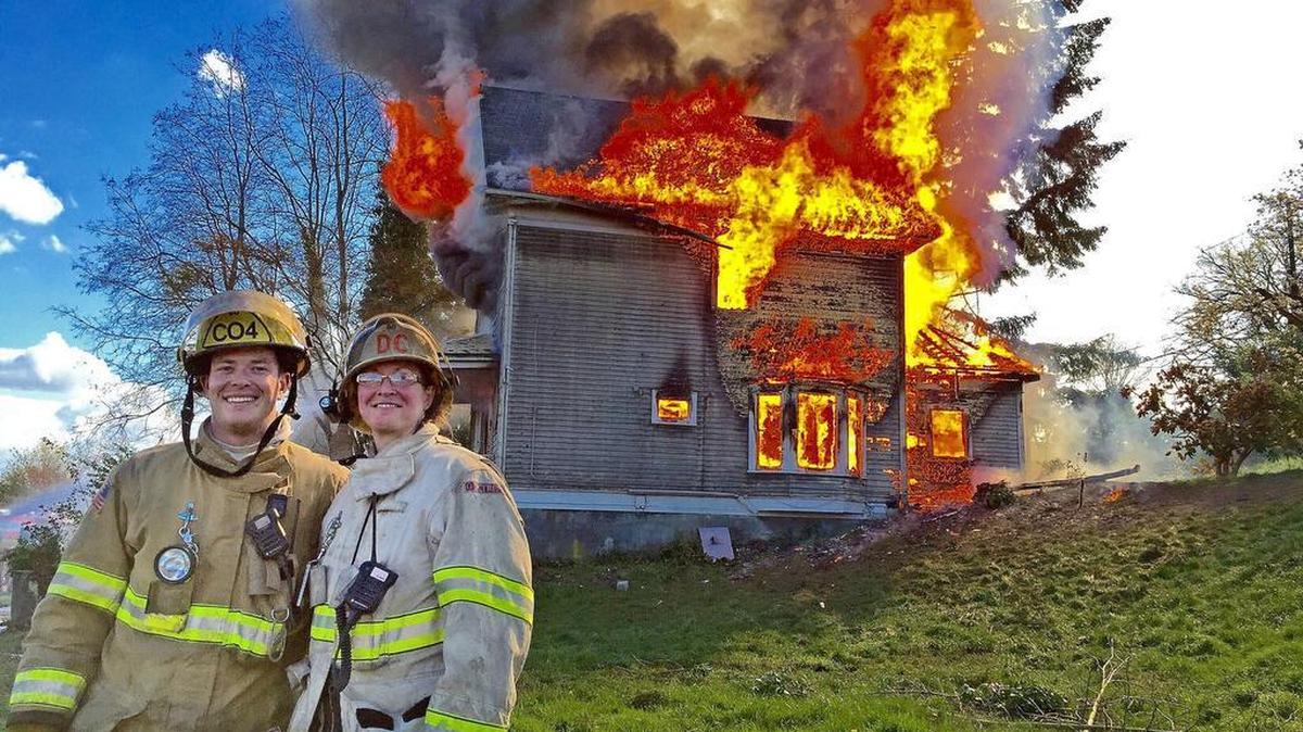 Probationary Tacoma firefighter Ramsey Mueller and his mother, Deputy Chief Faith Mueller, stand in front of a controlled training burn on March 26, 2016. Reportedly, Ramsey performed well in training before his death of a drug overdose on July 19, 2016.