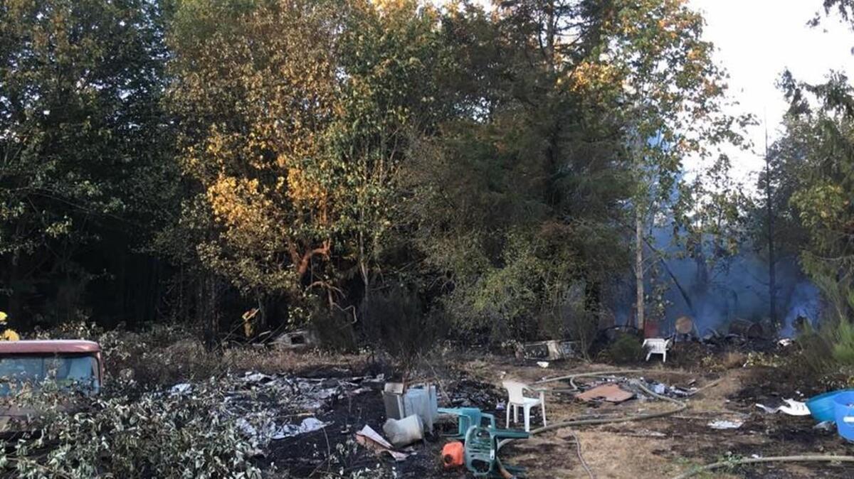 Smoke looms behind brush charred Monday night in a fire that burned an outbuilding on the Key Peninsula.
