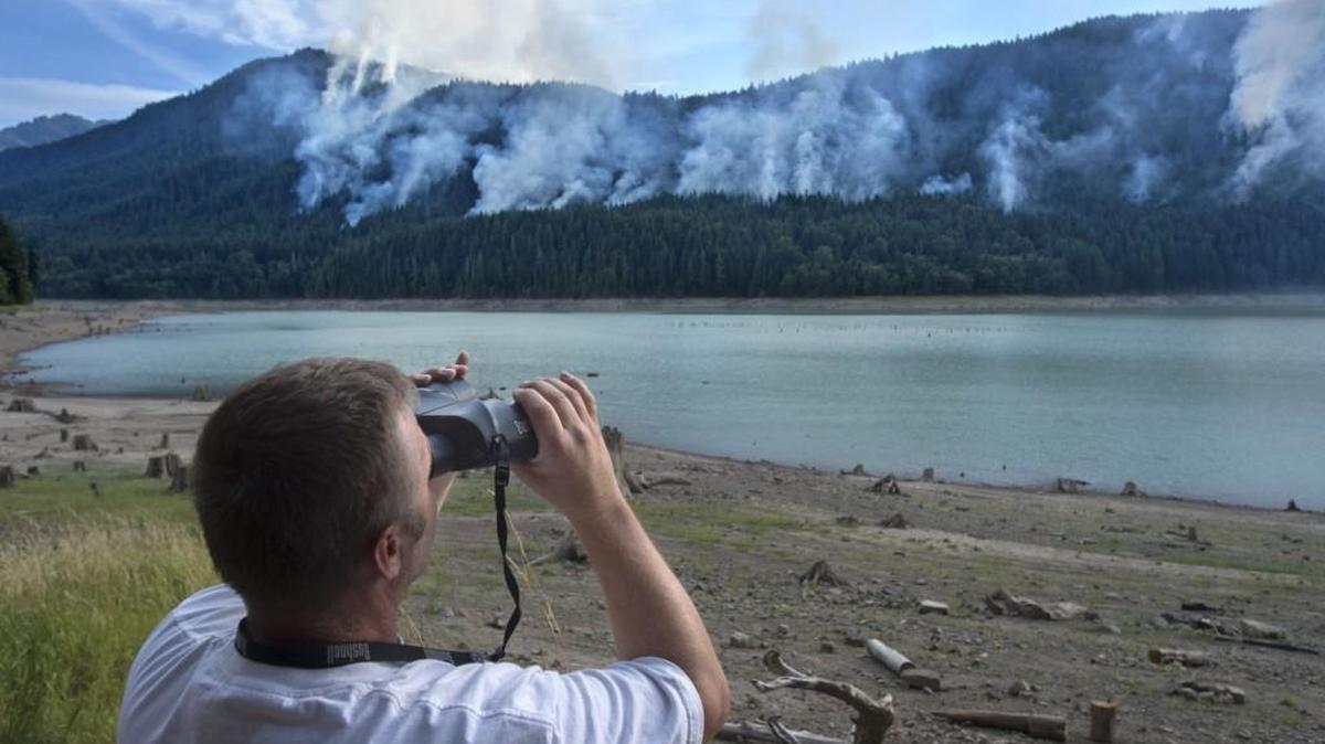 
Bill Lewis, an Eatonville real estate agent who is coordinating support for firefighters fighting the Alder Lake fire, watches the fire with binoculars on Thursday.
