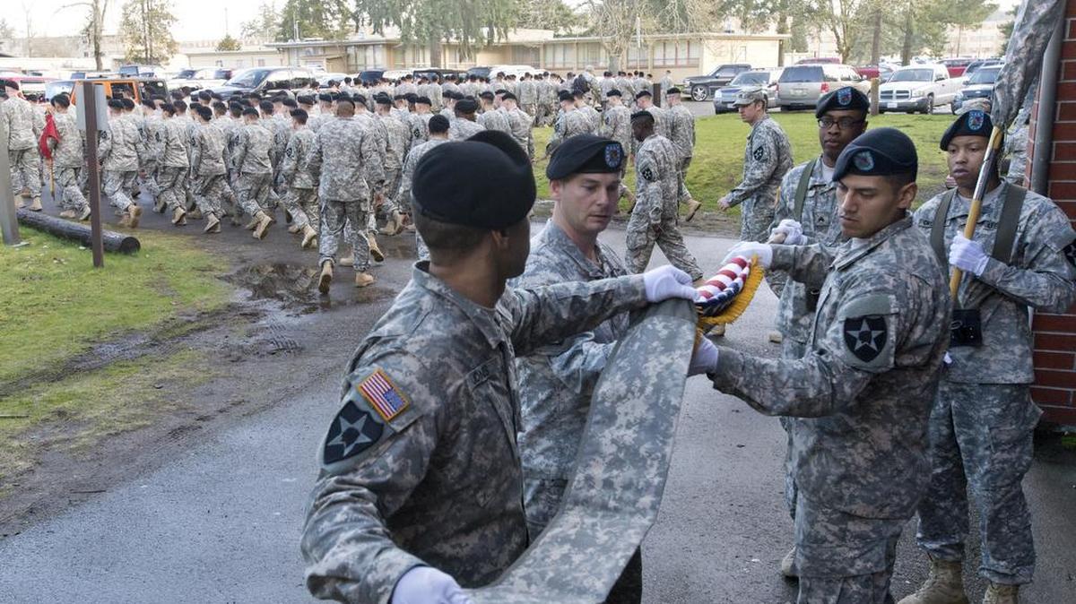 A color guard holds the cased colors of the 4th Stryker Brigade, 2nd Infantry Division, and cases the American flag after the brigade's inactivation ceremony at Joint Base Lewis-McChord in March 2014.