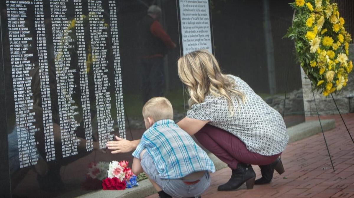 Traci Wise touches her husband’s name, Benjamin Wise, on the 1st Special Forces Group Memorial Wall while sharing a moment with her son, Luke, 6, during a memorial service at at JBLM on Thursday, May 26, 2016. Benjamin was lost in 2012 in Afghanistan.