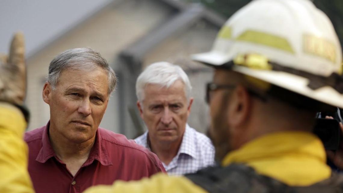 
Gov. Jay Inslee, left, and Robert Ezelle, Director of the Washington Military Department’s Emergency Management Division, look on as a firefighter explains to them ongoing efforts to fight a wildfire nearby, Thursday, Aug. 27, 2015, near Chelan, Wash. The complex of fires burning throughout the area are the largest in state history.
