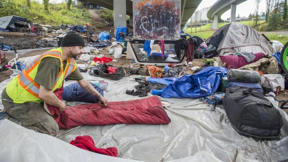 Craig Frady rolls up his sleeping bag while breaking down his tent site at a homeless camp underneath the Interstate 705 overpass that was closed by city and state officials in Tacoma on April 13, 2017. The Tacoma City Council recently passed an ordinance banning camping on public property within the city limits.