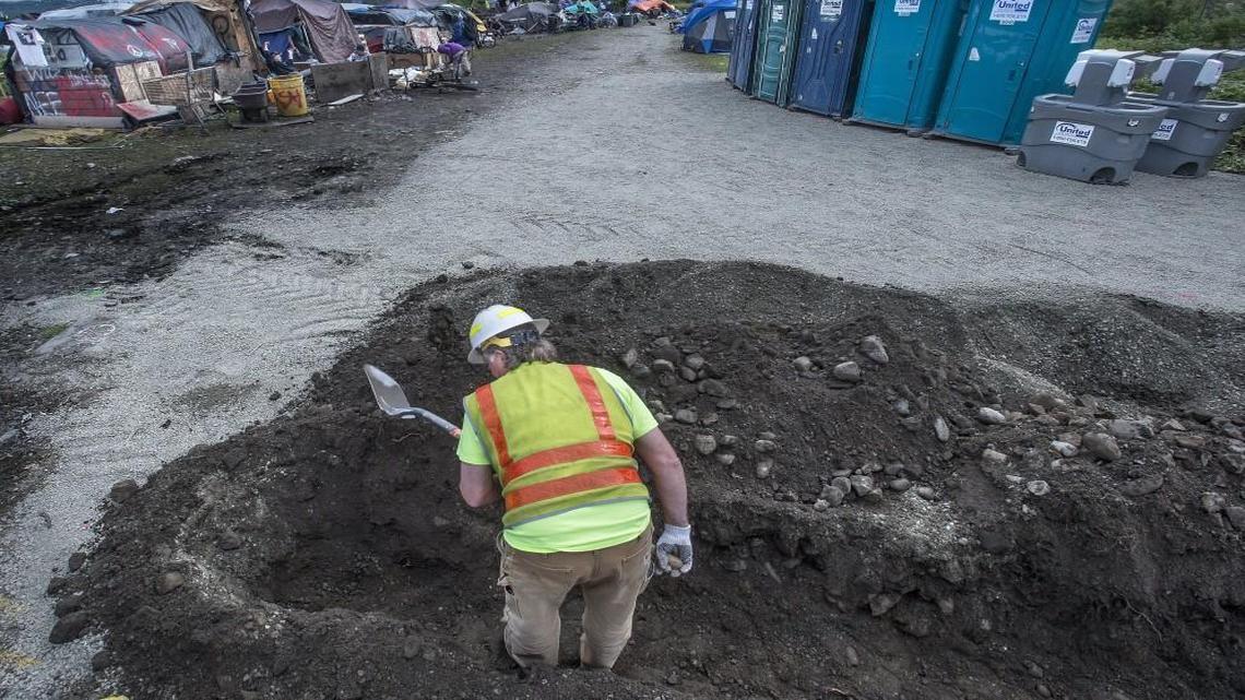 A City of Tacoma worker digs a trench that will bring water to a large homeless encampment near Portland Avenue and 18th Street East in May 2017. The city project also provided temporary washing stations, restrooms and and waste bins to improve health and sanitary conditions in the camp which serves as home to over 50 people.