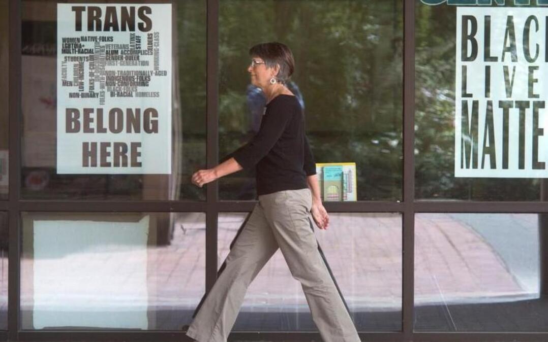 A woman walks past signs posted at The Evergreen State College campus in Olympia on Thursday, June 1, 2017.