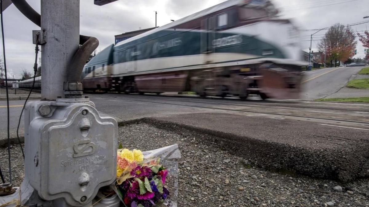 A train passes a bouquet of flowers sitting at the railroad crossing at the bottom of McCarver Street in the Old Town neighborhood of Tacoma on Tuesday.