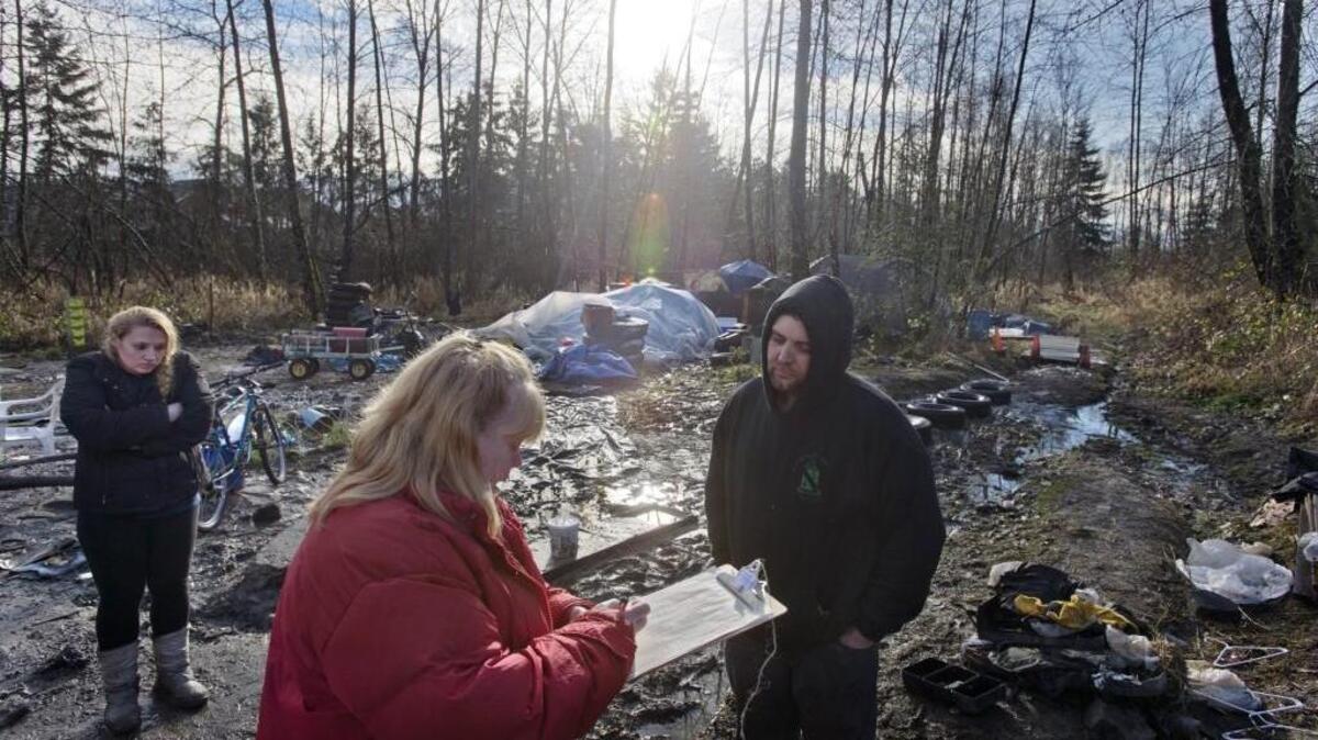 Volunteer Shirley McLaughlin interviews Ryan Degood of Parkland as Adriana Krieger of Tacoma waits in a muddy encampment in Parkland in 2013. The interview was part of the 2013 Pierce County homeless survey. Peter Haley / Staff photographer