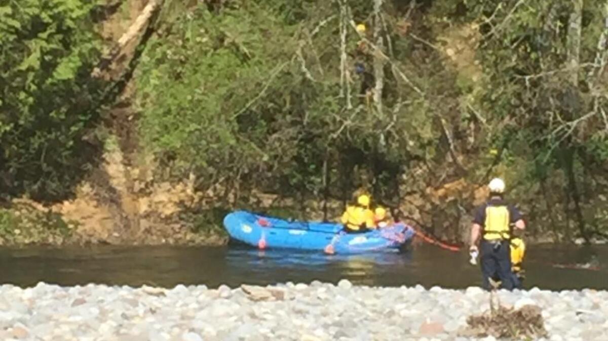 Rescuers wait in the Puyallup River on Thursday afternoon as they await two 15-year-old girls who got stuck on a hillside across the river from Orting.