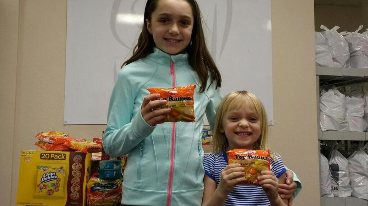 Addison Olson (left) asked for food for Christmas to give to the Homeless Backpacks program. The 9-year-old posed with her sister, Avery Olson, 5, at the organization’s headquarters when they dropped off their contributions.