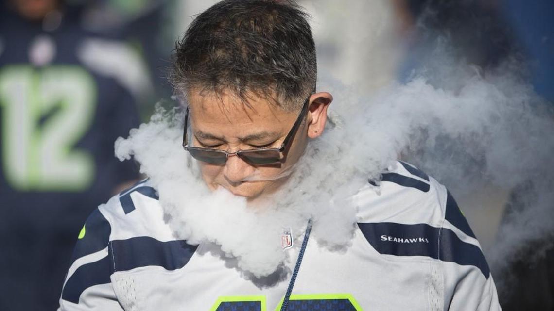 A Seahawks fan lets out a puff of vapor as he walks outside CenturyLink Field before the a game Oct. 5. A lawsuit protesting new rules in Pierce County that made e-cigarettes subject to the same restrictions state law places on smoking in public places was filed Tuesday in Thurston County Superior Court.