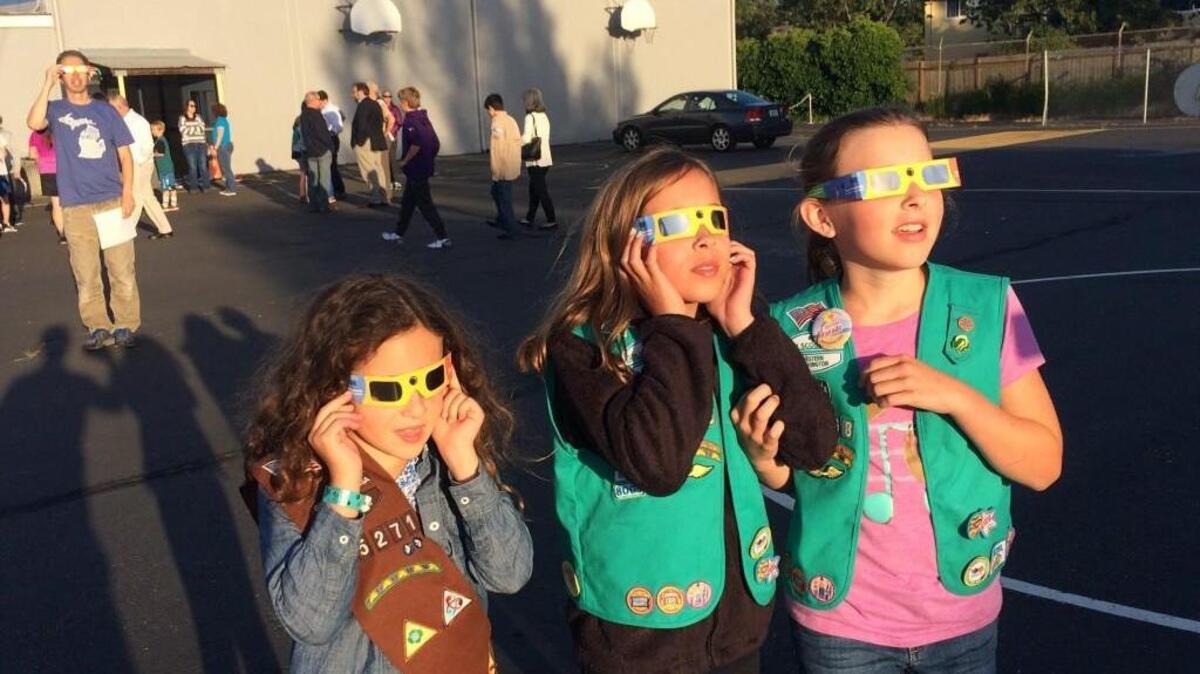 From left, Anna, 8, and her sister Clara, 10, Rosati, along with friend Charlotte Savage,10, look at the sun at St. Charles Borromeo Parish in Tacoma using special glasses designed to safely view it.