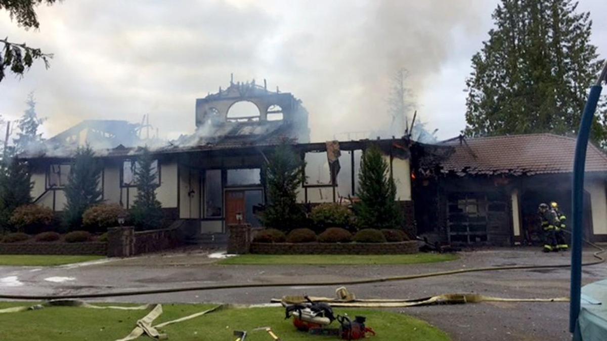 Smoke billows from the wreckage of a home on Lake Tapps’ Snag Island after an early Sunday house fire.