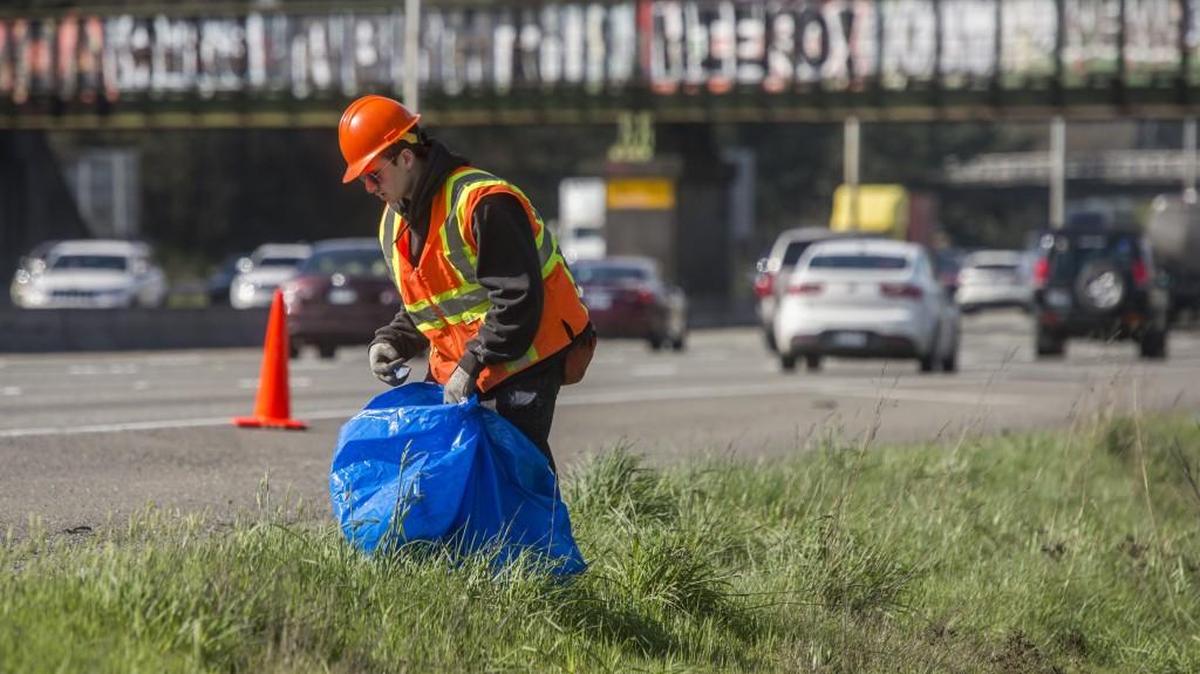 Eli Neuman-Hammond picks up litter April 3 on the shoulder of Interstate 5 in Lakewood along with others from the Department of Ecology’s Youth Corps.