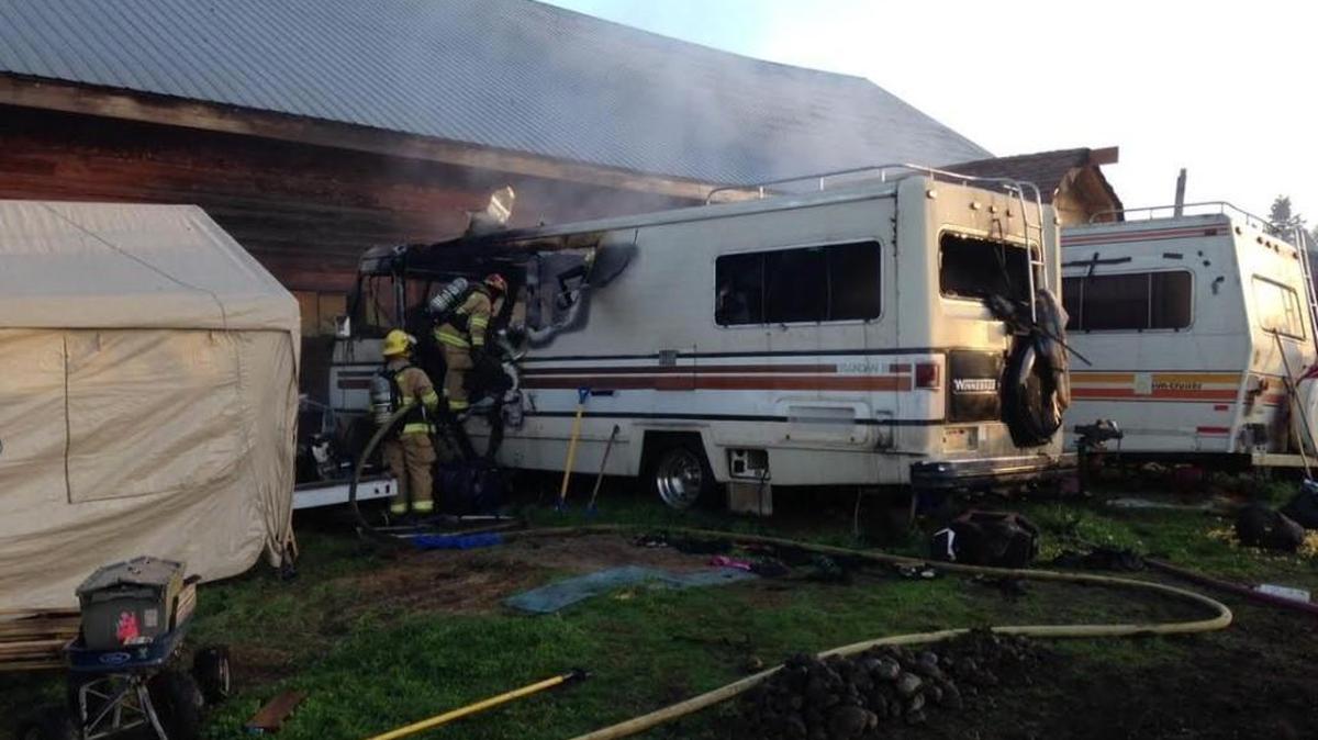 Firefighters check the interior of a burned out recreational vehicle where a woman and two dogs were found dead Wednesday.